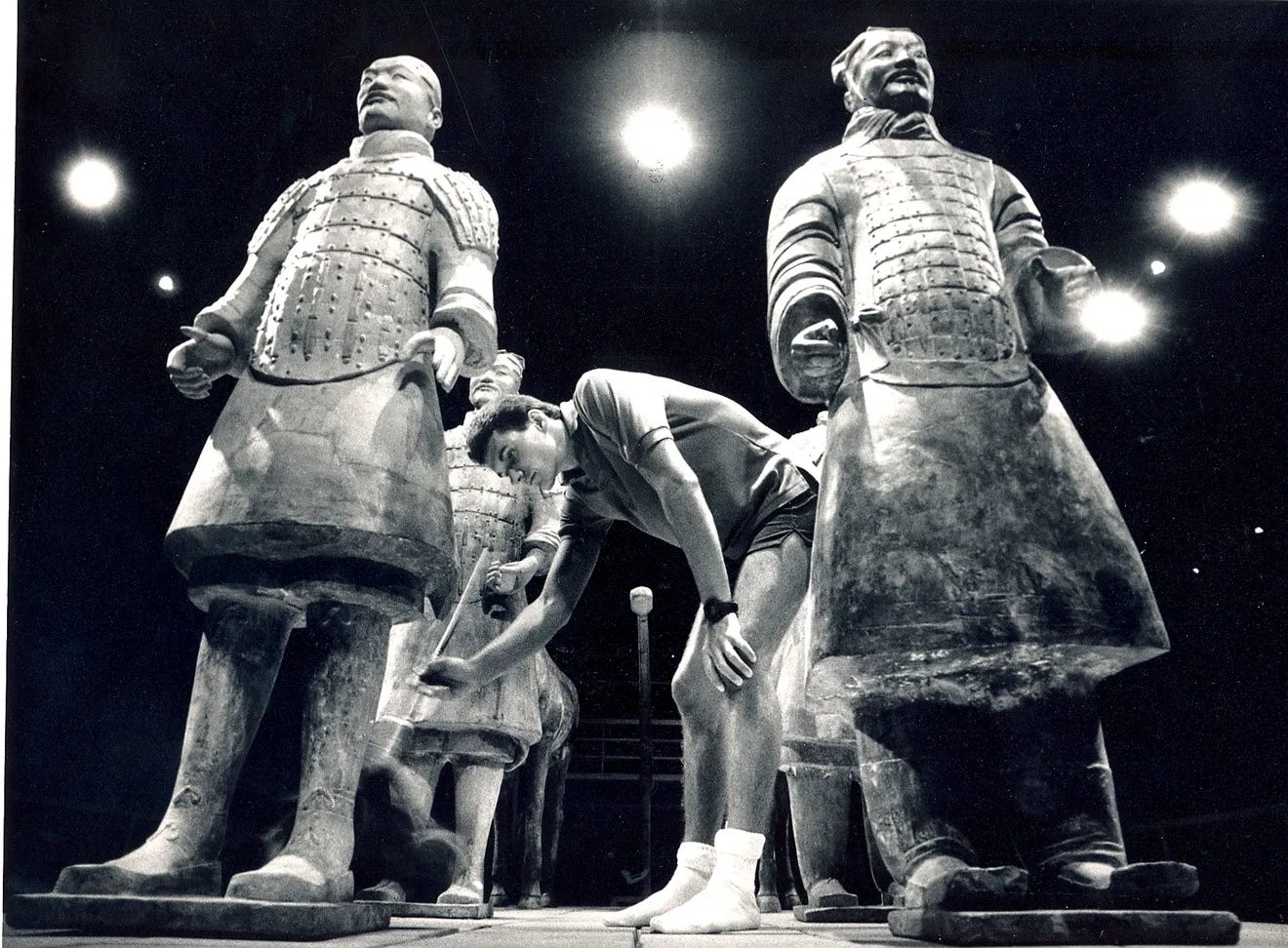 A white American dusts a display of Terracotta Warriors, black and white photo