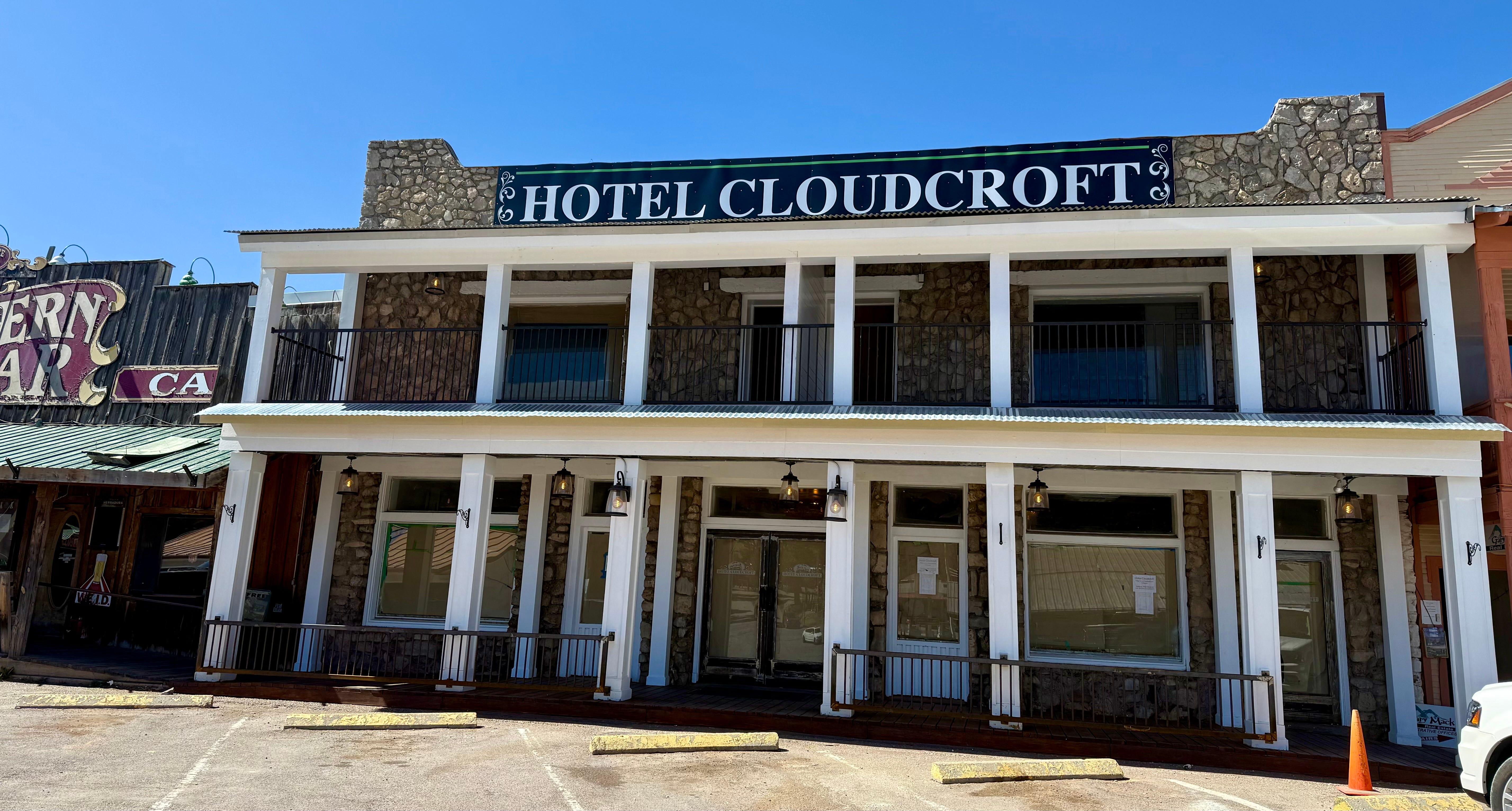 Hotel Cloudcroft next to the Western Bar and Cafe and other shops on Burro Avenue in Cloucroft New Mexico. A rock building with white pillars