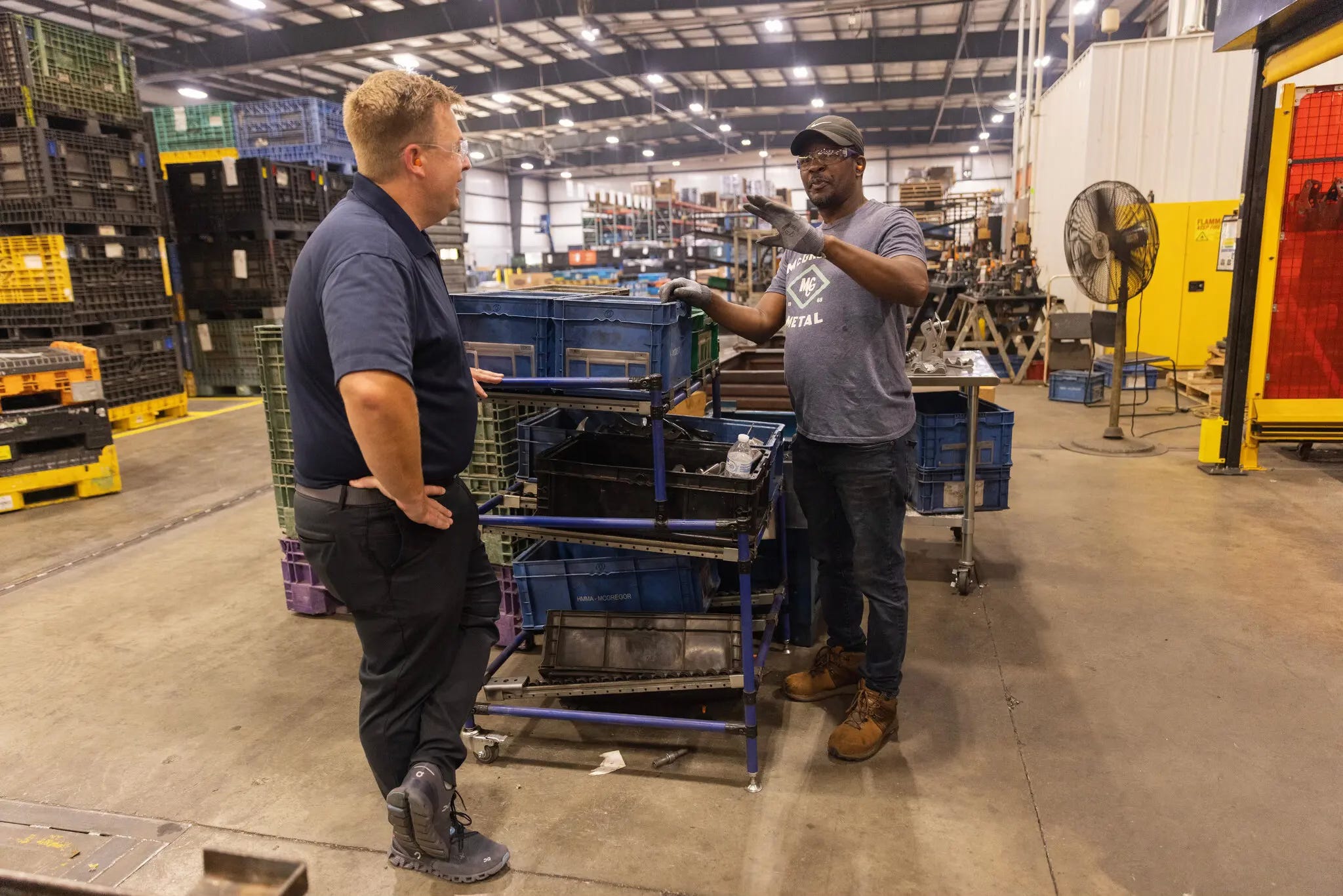 Jamie McGregor, left, the chief executive of McGregor Metal, an automotive parts maker in Springfield, talks with Daniel Campere, a Haitian worker. Photo: Maddie McGarvey for The New York Times.