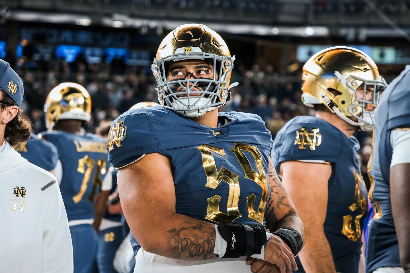 Sean Sevillano looks up to his right while holding his wrist on the sideline next to teammates during a Notre Dame Fighting Irish football game