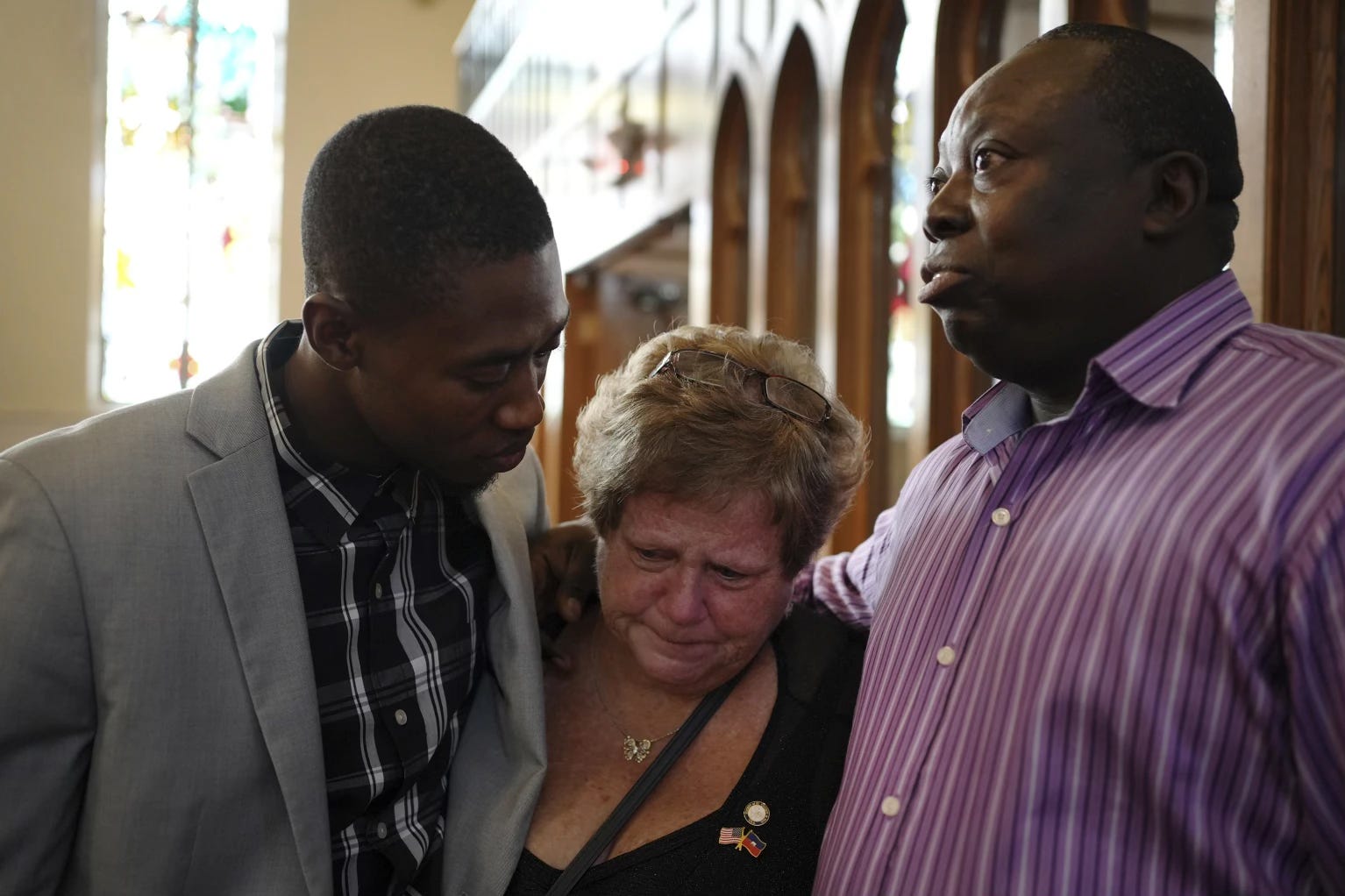 St. Raphael Catholic church parishioners Berthing Jean Philippe, left, Casey Kelly Rollins, and Patrick Joseph embrace after a service supporting the Haitian in Springfield, Ohio, Sunday, Sept. 15, 2024. Photo: Luis Andres Henao/AP.