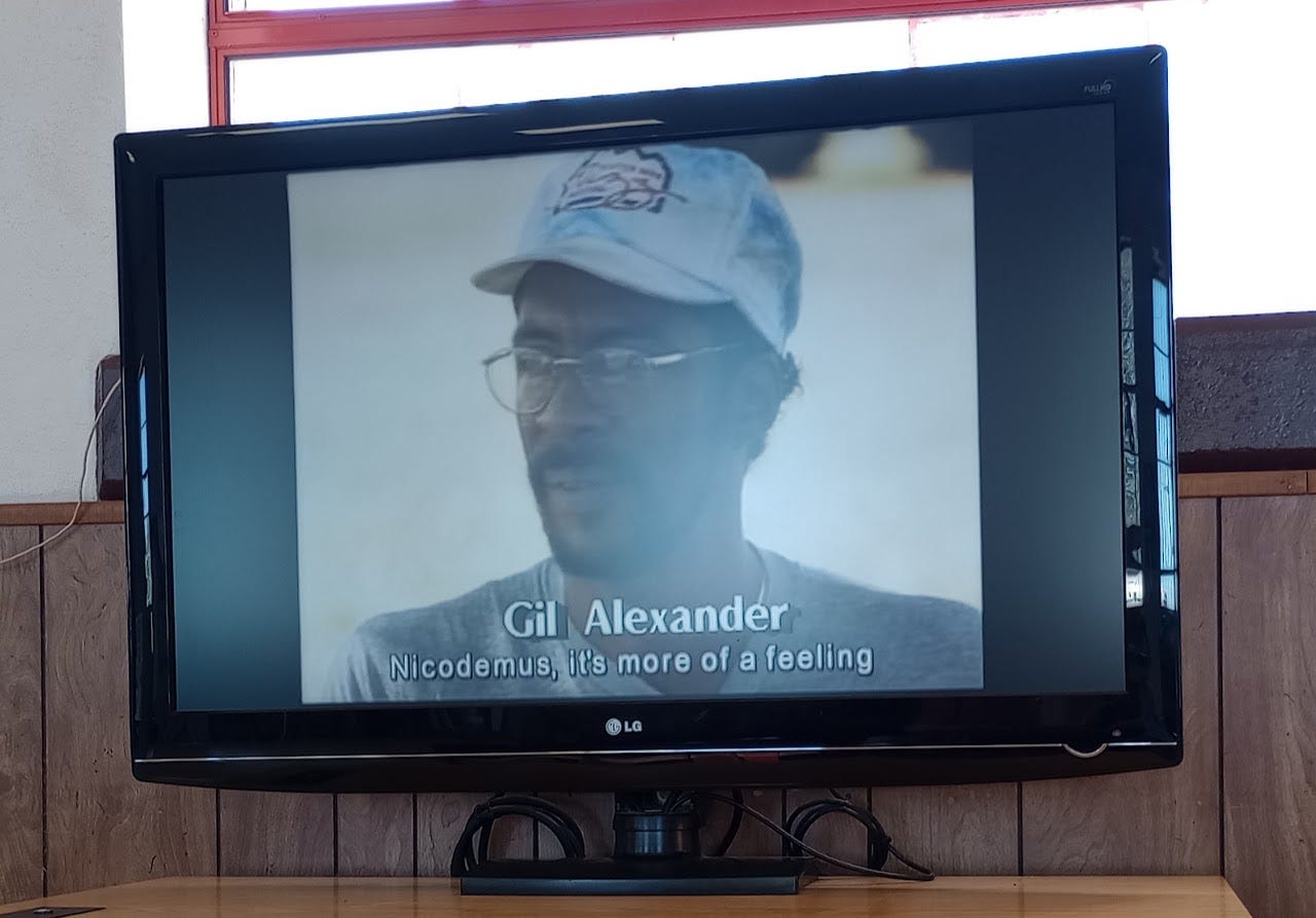 Black man in baseball cap and glasses with caption Gil Alexander