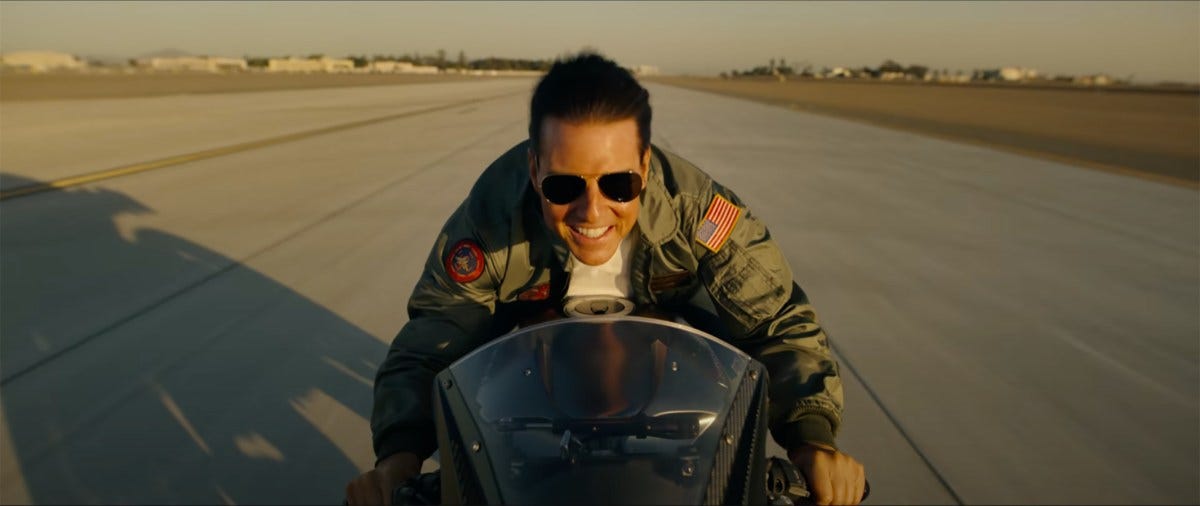 Tom Cruise rides a motorcycle down a stretch of runway with a smile on his face. Without a helmet. The image fits the entire width of the screen, breaking the rules of the previous pictures.