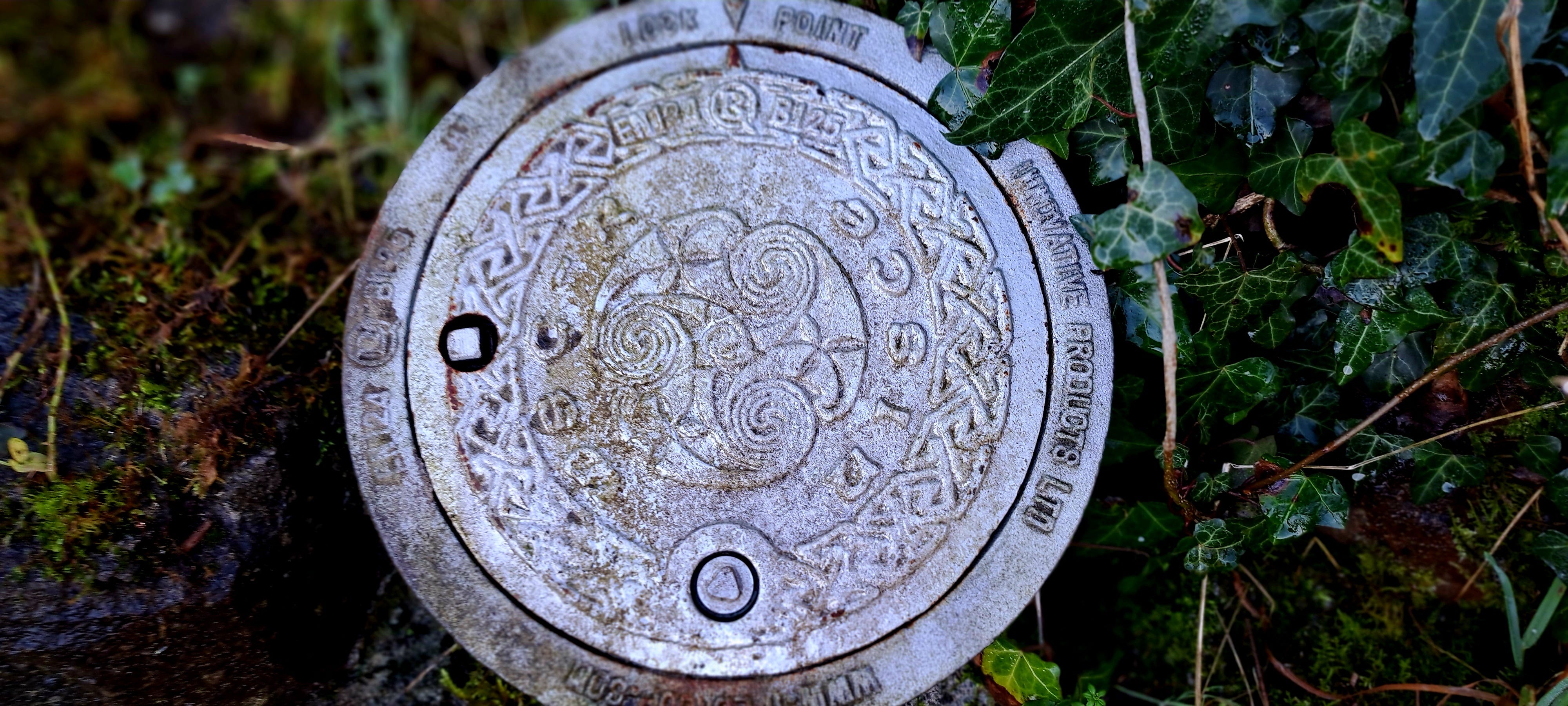 A circular metal water stopcock embossed with the triskele and other Irish knotwork designs and the Irish word for water, 'uisce'... sounds like ishka