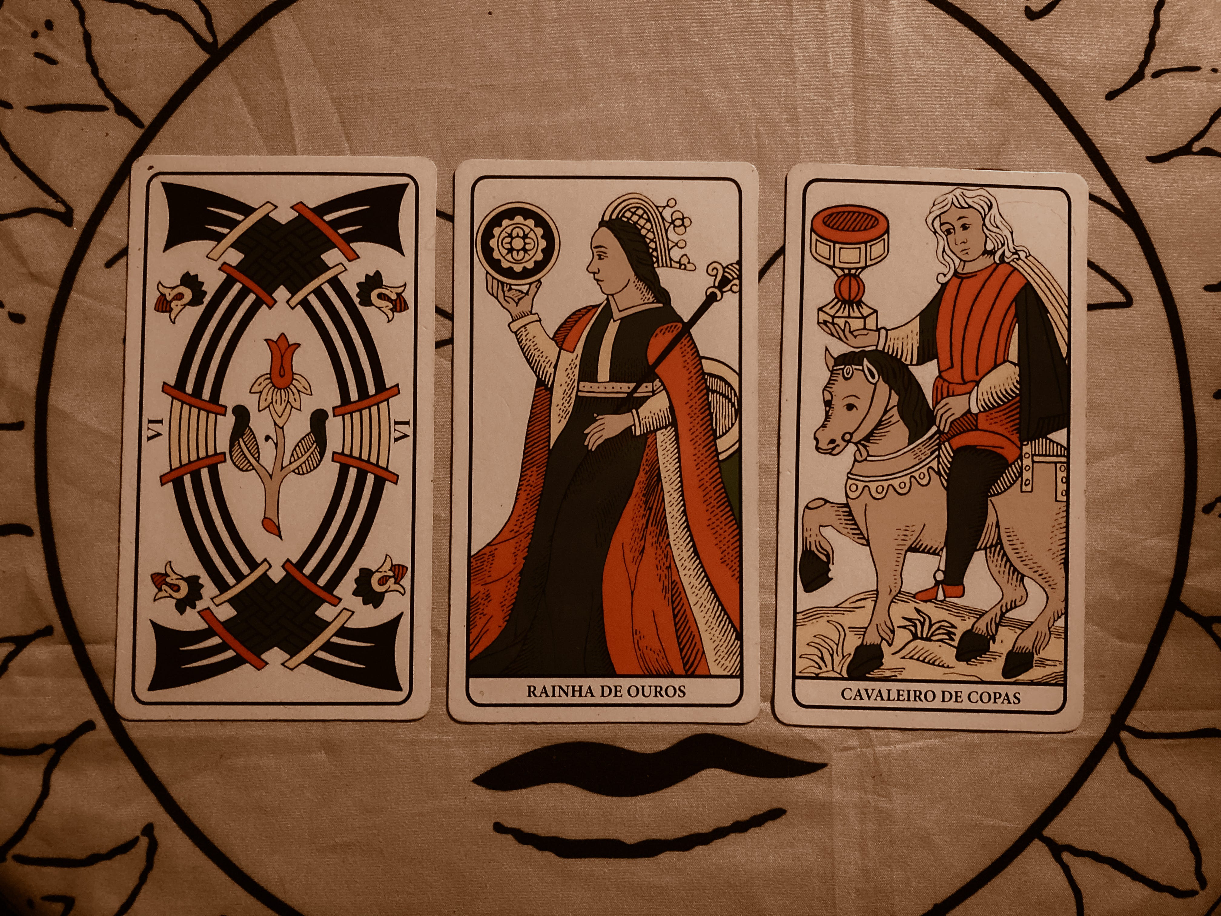 Três cartas de tarot dispostas sobre mesa forrada com toalha do arcano O Sol