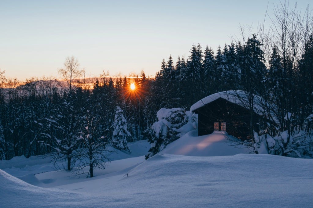 Winter cabin in the gloaming of setting sun.