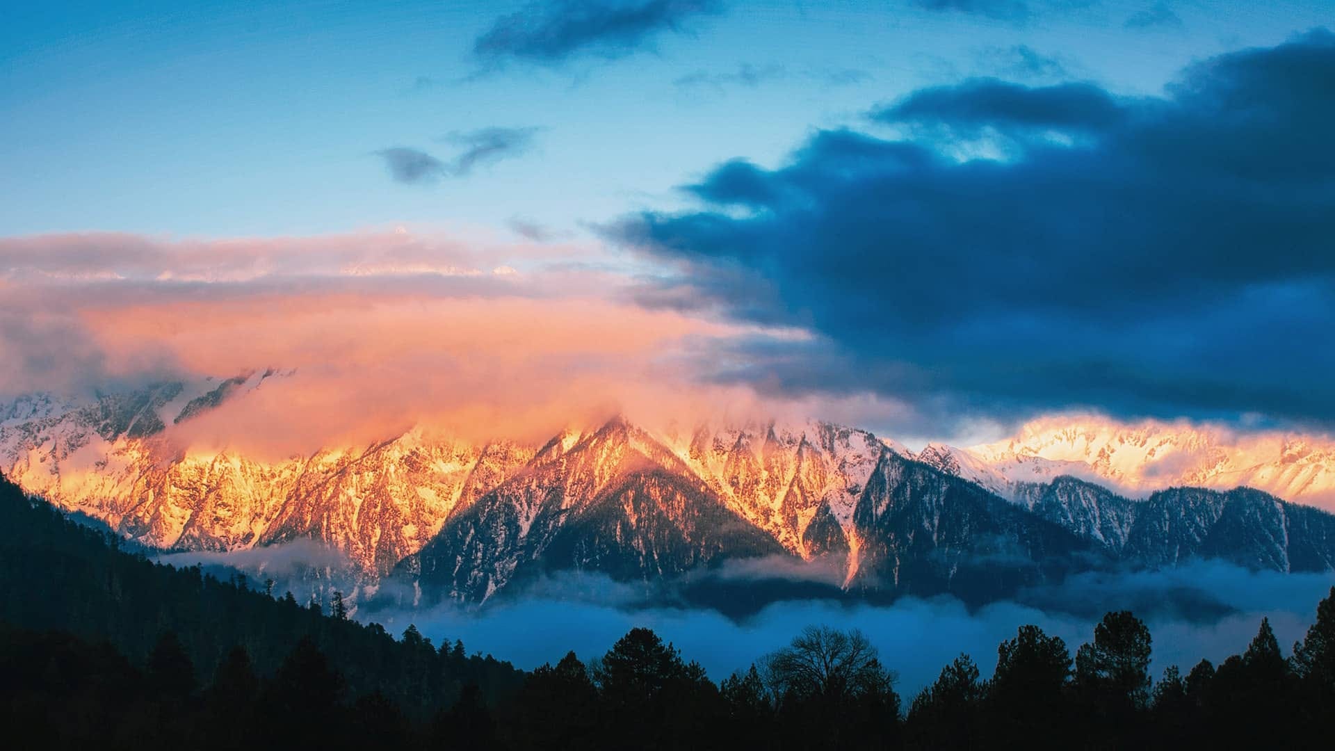 Rugged mountaintops illuminated by the warm glow of sunrise.