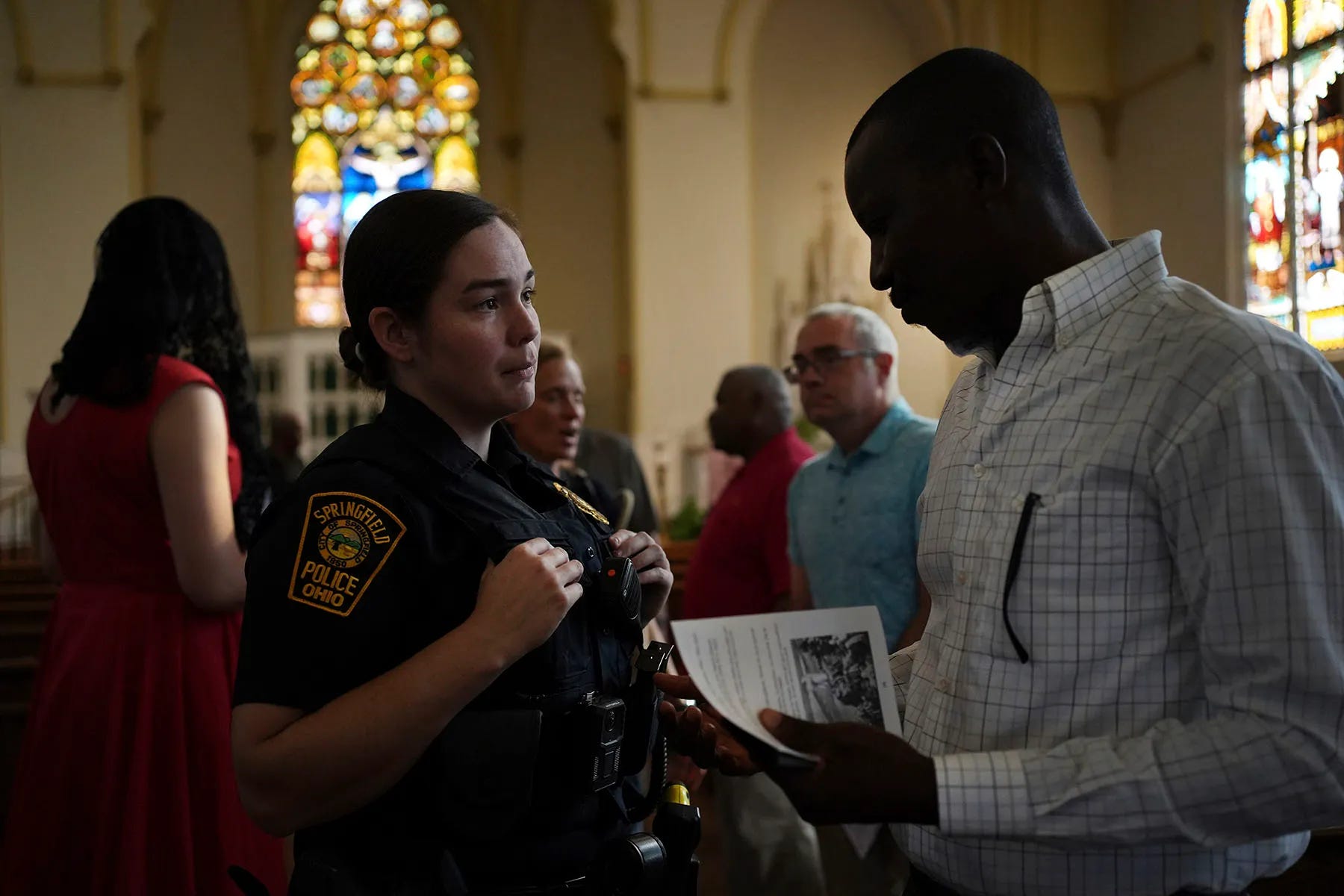 A Springfield police officer chats with parishioners after a service in support of the Haitian community at St. Raphael Catholic church in Springfield, Ohio.