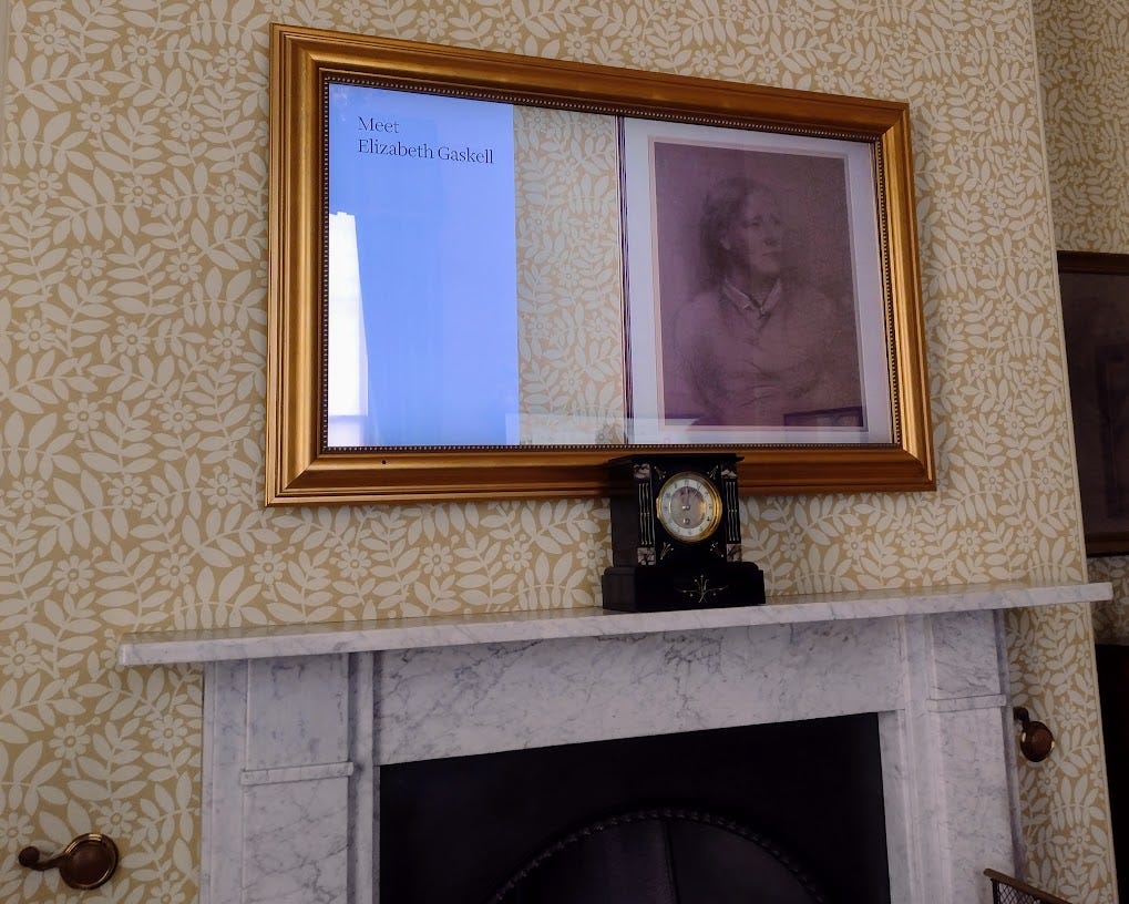 Video screen over fireplace that says Meet Elizabeth Gaskell, with portrait drawing of woman