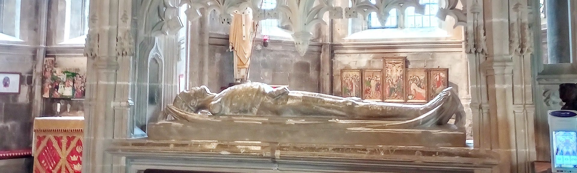 Emaciated corpse replica made from stone, lying in open tomb in church