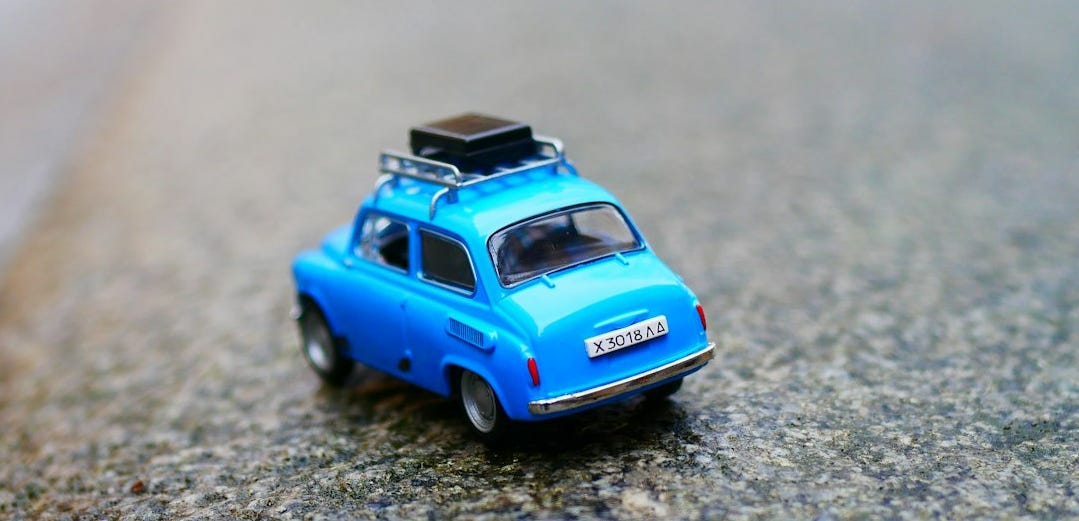 Blue toy car on what appears to be asphalt. Photo by Karine Germain on Unsplash