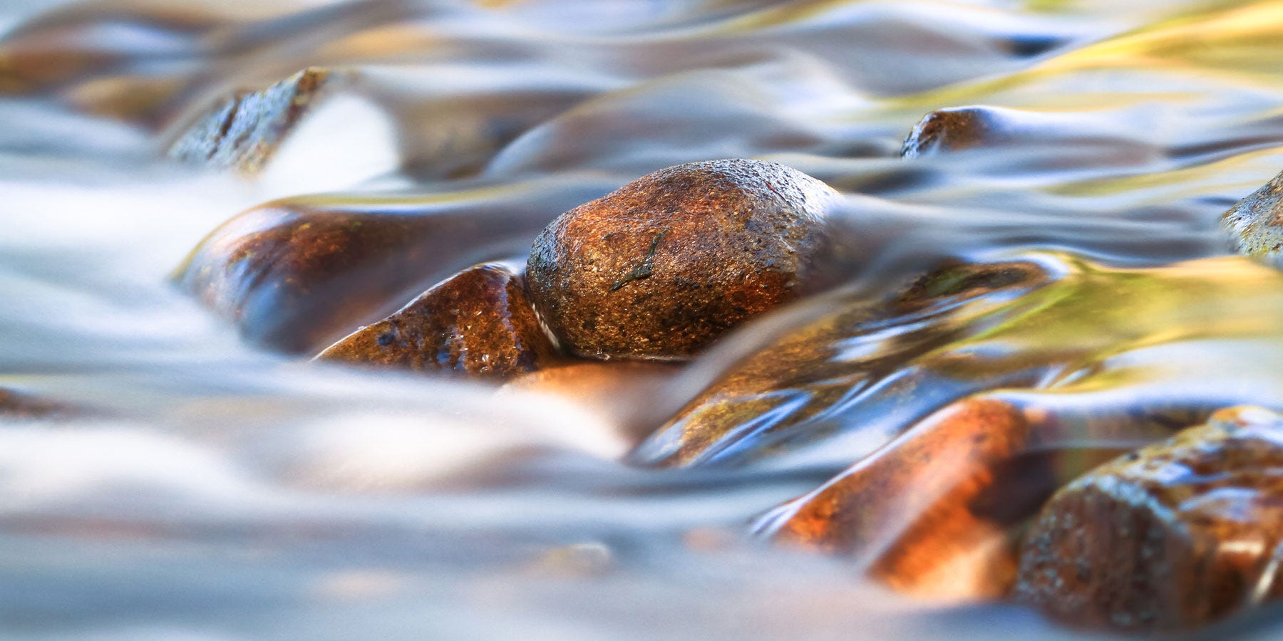 Blurred water running over river rock representing writing flow state.