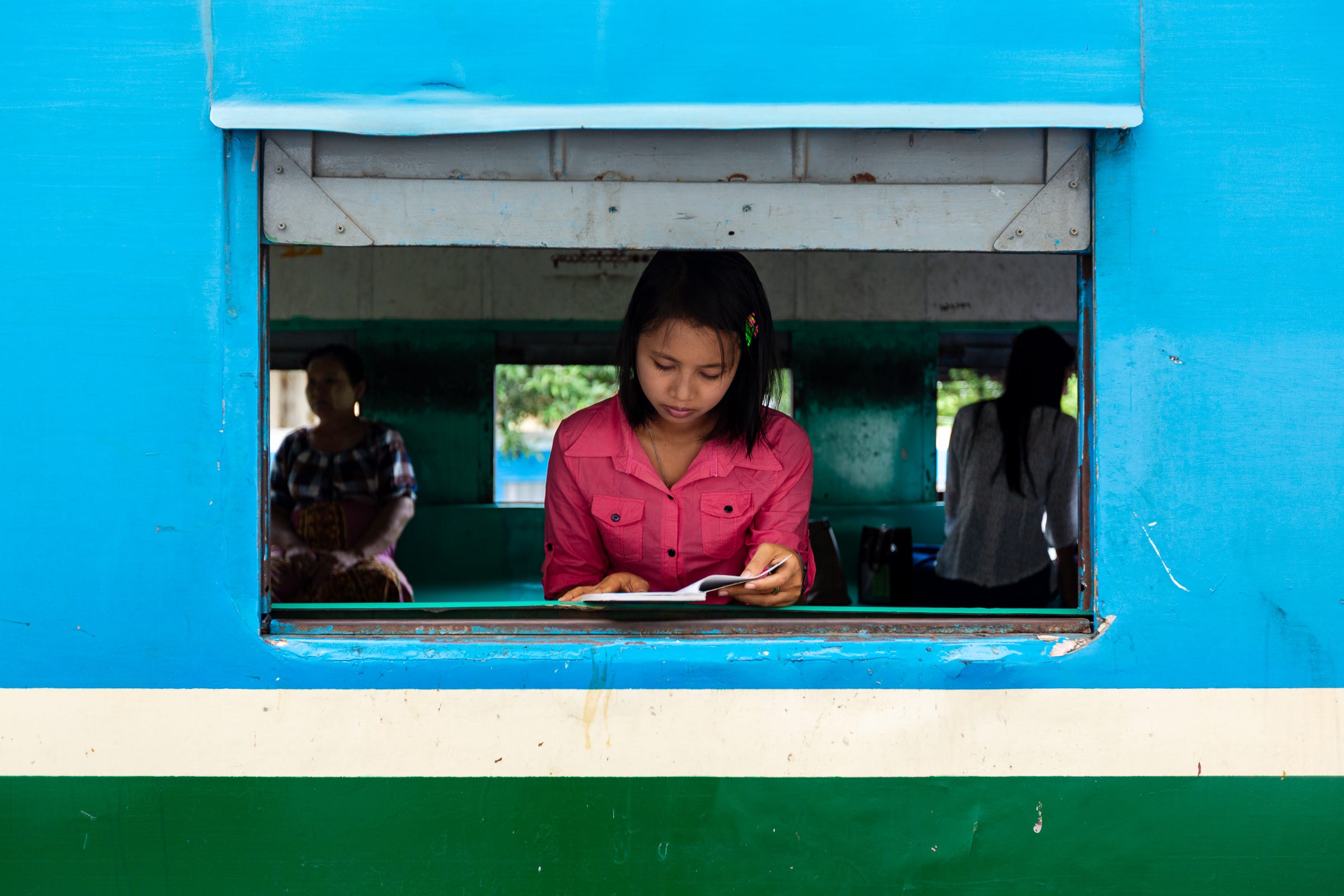 Reading in an open train carriage window, Yangon, Myanmar. © Gavin Gough. 1/50, ƒ2.8, ISO 100, 35mm