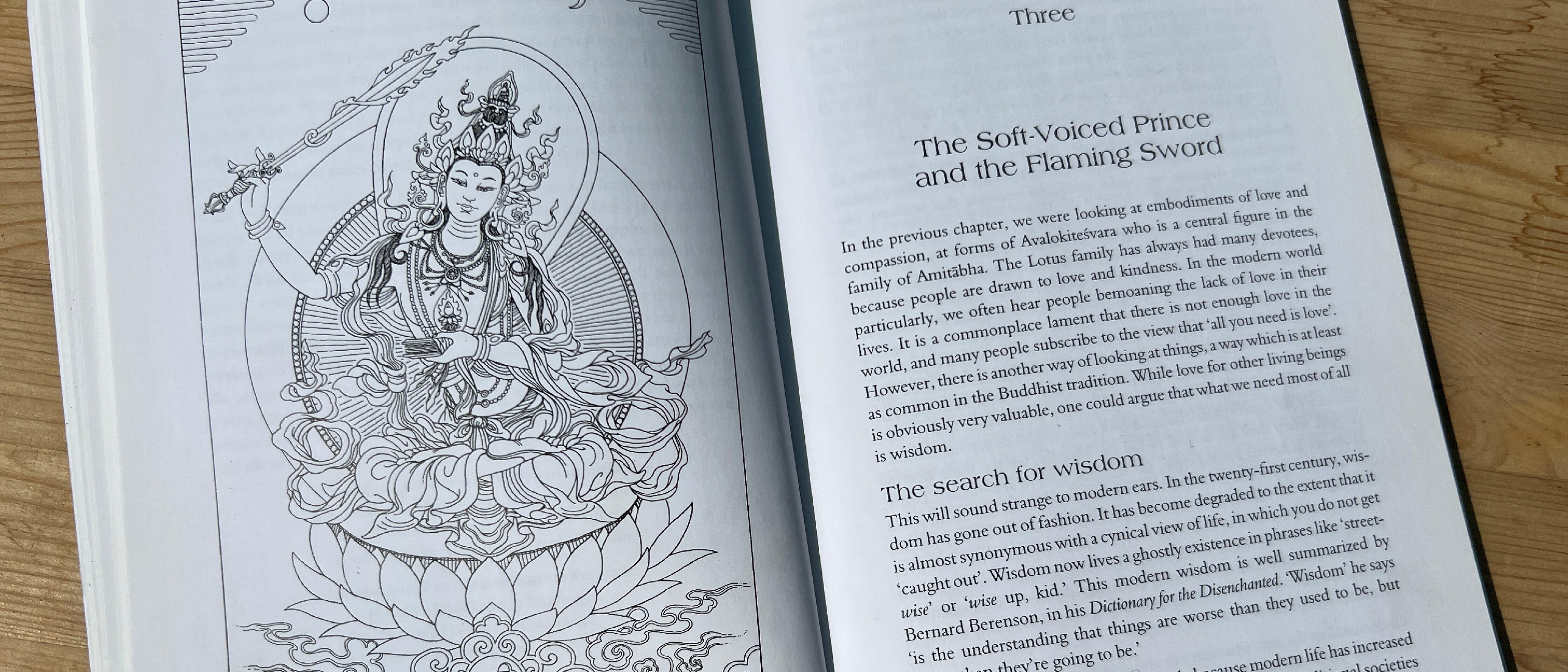 Photo taken of a book open to an image plate and start of a chapter. The image plate, on the left page, shows a detailed line drawing Thangka of the Bodhisattva Manjushri adorned in jewelery, holding aloft a flaming sword. The right hand page indicates this is the third chapter of the book, which is titled The Soft-Voiced Prince and the Flaming Sword. 