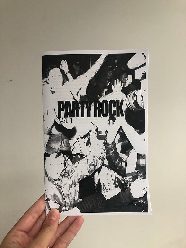 a photo of my hand holding a zine, with a black and white cover of people partying, which says PARTY ROCK Vol. 1 on it
