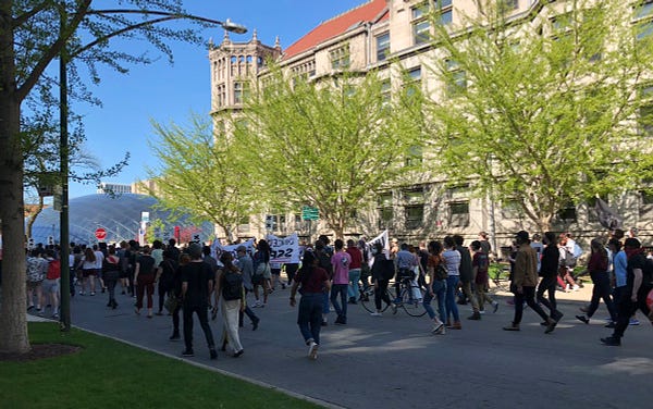 The crowd departs from Levi Hall after hearing from speakers from Graduate Students United and Lift the Ban, filling the street and turning down the intersection with banners and picket signs
