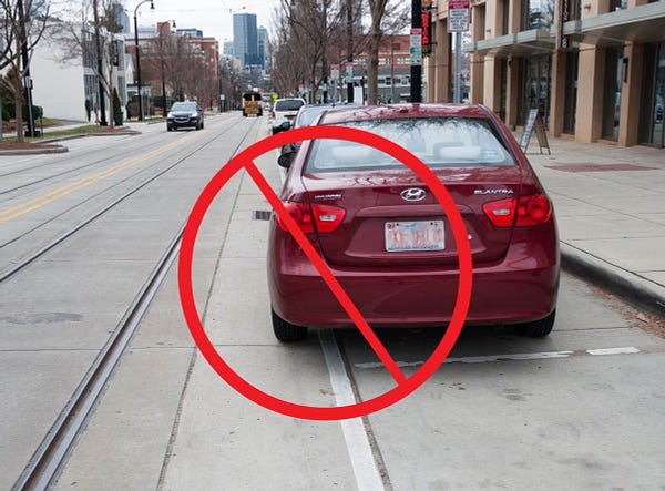 Car with a "NO" symbol over in near streetcar tracks.