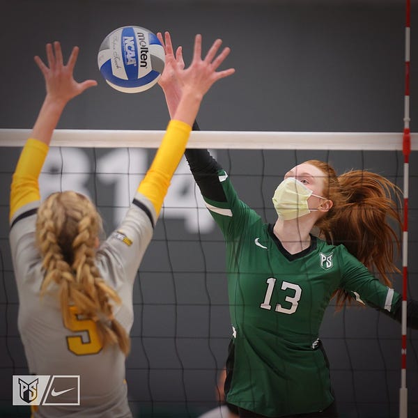 Action photo of Portland State volleyball player hitting a ball around an Idaho blocker at the net during a match.