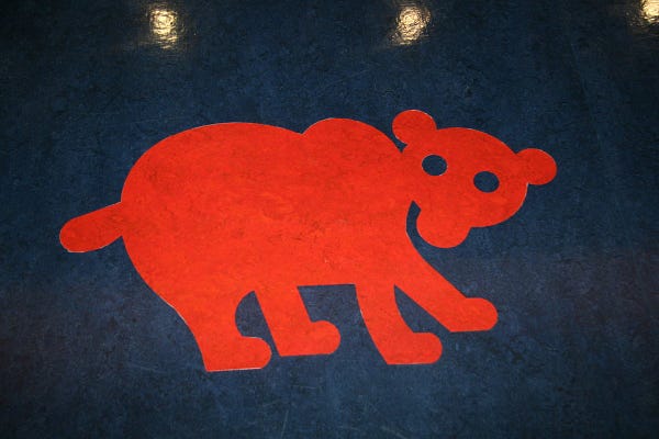 Photograph of a stylized bear on a blue floor.