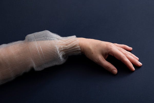 A left hand and forearm wearing a sleeve of fabric-fiber with digital capabilities.