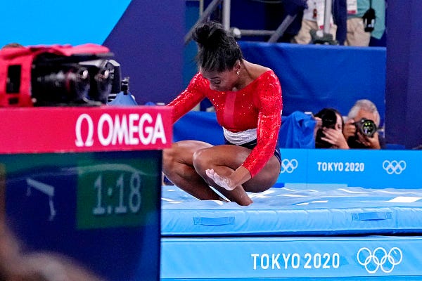 Simone Biles crouches on the mat after competing on the vault.
