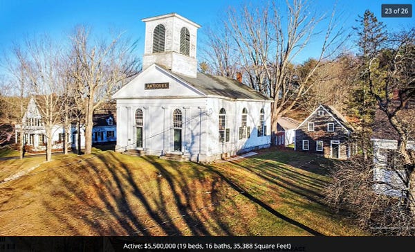 A New England village, white wooden church with a sign marked antiques, surrounded by leafless trees and several other mid-19thc buildings