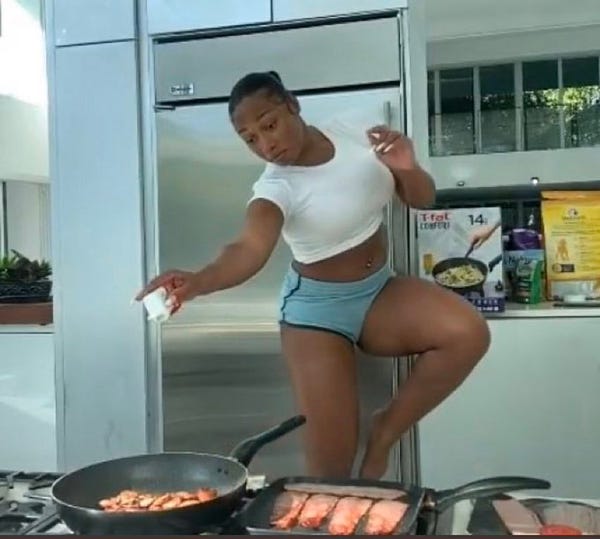 Megan Thee Stallion dashing some pepper into a pan while skipping through the kitchen