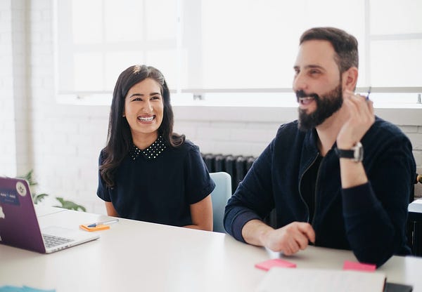 Two business people smiling during workday. You X Ventures Studio, Toronto. Unsplash License