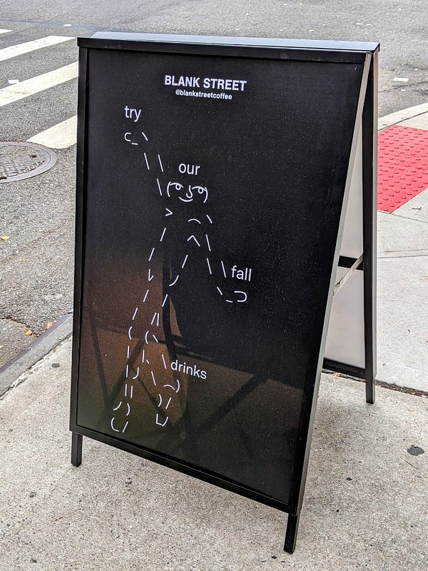 Sidewalk sign for Blank Street Coffee featuring ASCII art and the words "try our fall drinks"