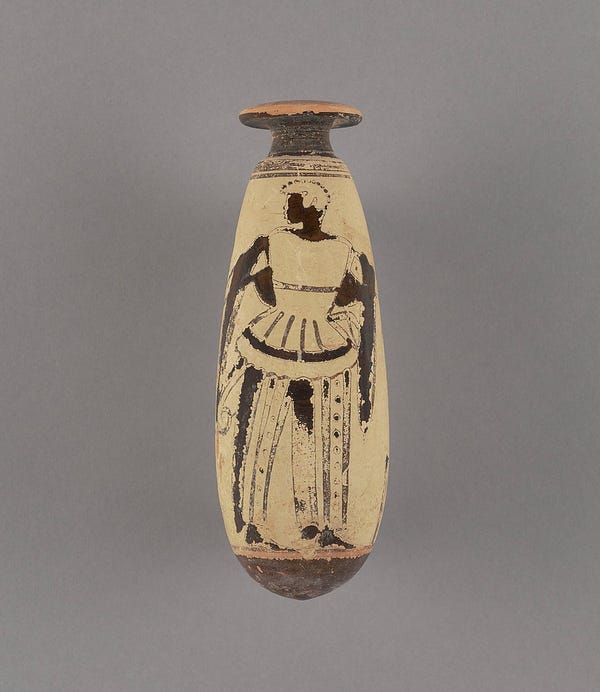 A beige terracotta vessel shaped like a long tear drop. A dark-skinned figure faces left wearing striped pants and a draped mantle holds an ax and an arrow.