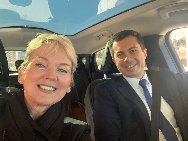Secretary Granholm and Secretary Buttigieg take a selfie before riding in an EV car.