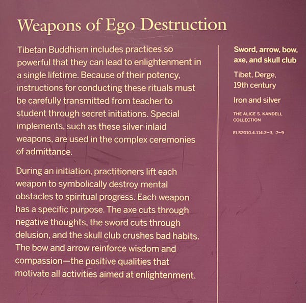 Museum caption. It reads: 

Weapons of Ego Destruction
Tibetan Buddhism includes practices so
powerful that they can lead to enlightenment in
a single lifetime. Because of their potency,
instructions for conducting these rituals must
be carefully transmitted from teacher to
student through secret initiations. Special
implements, such as these silver-inlaid
weapons, are used in the complex ceremonies
of admittance.
During an initiation, practitioners lift each
weapon to symbolically destroy mental
obstacles to spiritual progress. Each weapon
has a specific purpose. The axe cuts through
negative thoughts, the sword cuts through
delusion, and the skull club crushes bad habits.
The bow and arrow reinforce wisdom and
compassion--the positive qualities that
motivate all activities aimed at enlightenment.
