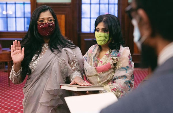 Shahana stands next to her mother in New York City Council chambers while taking the oath of office. Shahana’s right hand is raised and her left hand is placed on a Quran that her mother is holding.
