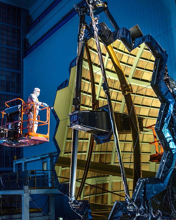 The James Webb Space Telescope's primary mirror during "center of curvature" mirror testing at NASA's Goddard Spaceflight Center. The technician, on left, shines a flashlight at the mirror.