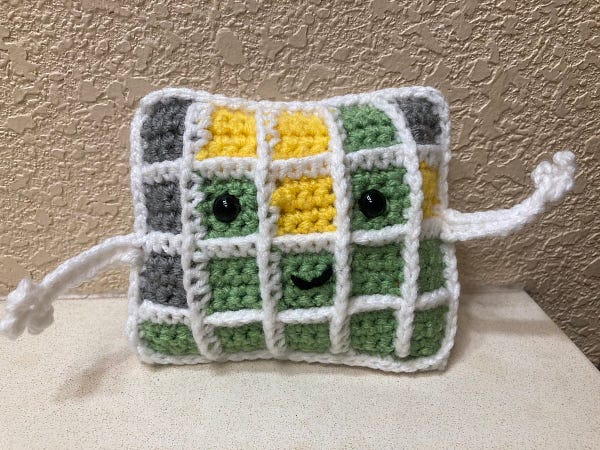 A smiling rectangle made up of green, gray, and yellow squares. He has eyes and a smiley face and two arms