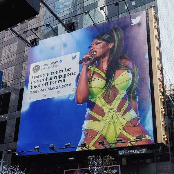  Image of a billboard in New York of a Tweet from Megan Thee Stallion that reads "I need a team bc I promise rap gone take off for me" from May 2014. The Tweet is overlaid on an image of her performing.
