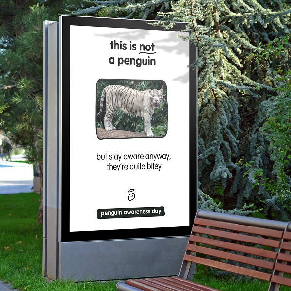 This hoarding is in a park by a bench. And it's of a white bengal tiger. It says, "this is not a penguin. But stay aware anyway, they're quite bitey."
