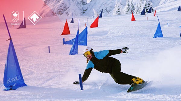 Snowboarder heads down a hill. She is leaned over touching the snow as she makes a turn. 