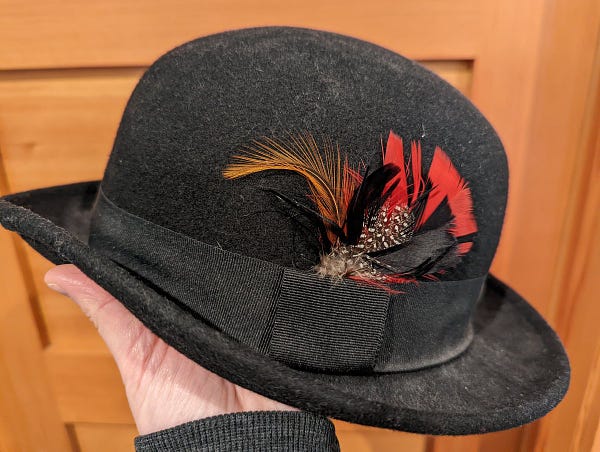 A dusty black hat with a spray of colorful feathers stuck into the hat band
