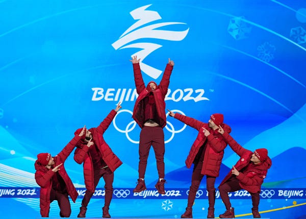 A man jumping in the centre of the photo with two guys on each side pointing at home 