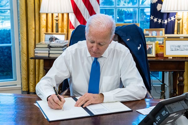 President Biden signs an executive order in the Oval Office