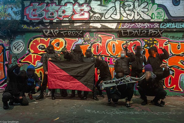 Anarchists and anti-fascists standing in front of mural