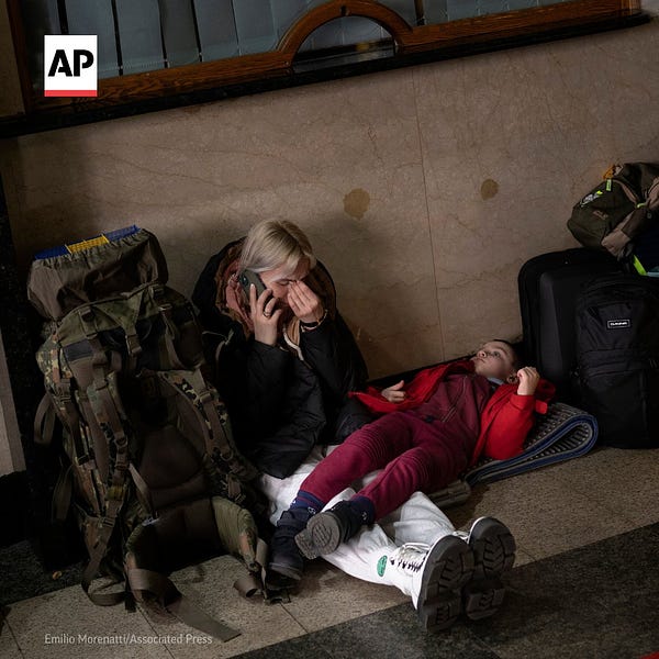 A woman sits with her daughter waits for a train as they try to leave Kyiv, Ukraine.