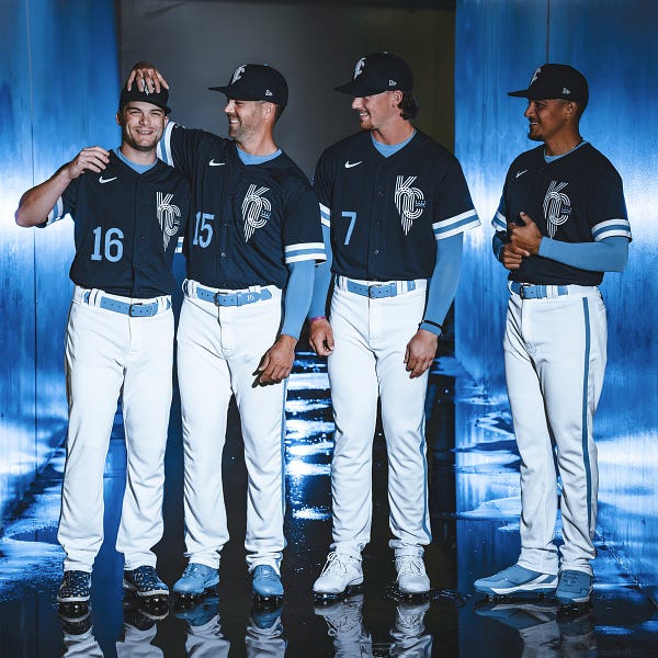 Andrew Benintendi, Whit Merrifield, Bobby Witt Jr. and Nicky Lopez smiling in a blue lit tunnel wearing the new Royals City Connect uniforms.