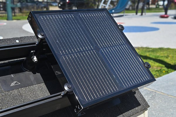 A black solar panel. There is a playground blurred in the background. 