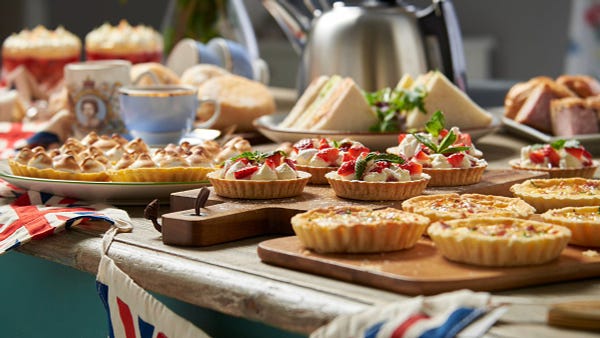 A selection of food to celebrate the Queens Jubilee including Quiche Lorraine, Eaton Mess, Lemon Meringue Pies, Sandwiches and a cup of Tea.