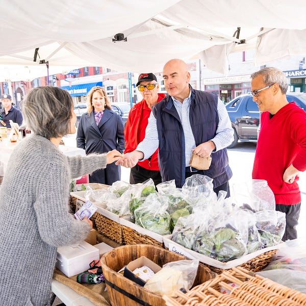 Steven Del Duca interacts with a small business vendor after a purchase, as Ontario Liberal candidate, Ted Hsu and others look on in Kingston. 