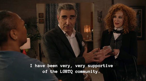 Schitt’s Creek Ronnie’s Party. Johnny and Moira at Ronnie’s house. Johnny Rose speaking to Ronnie captioned “I have been very, very supportive of the LGBTQ community.”
Moira Rose to Johnny Rose captioned “Oh, John... John…”
Johnny Rose back to Moira captioned “Did I leave out a letter?”