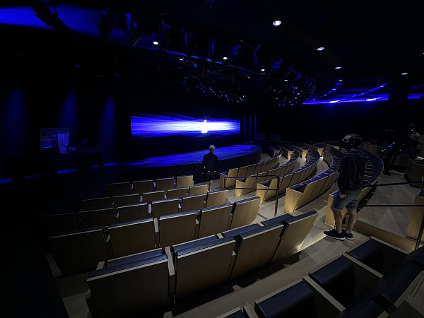 A row of theater seating, with a dark blue screen at the front.