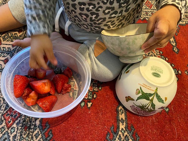 My toddler holding the small, chipped bowl on one hand and eating fruits with her other hand. Big bowl is upside down on the carpet!